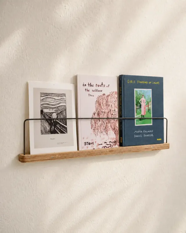 Angled view of the Art Ledge displaying three art books in warm natural light